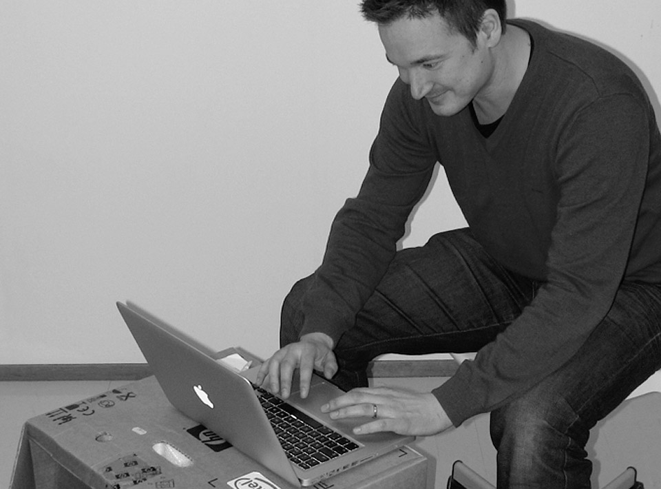Ilkka sitting at his cardboard desk at the Espoo office.